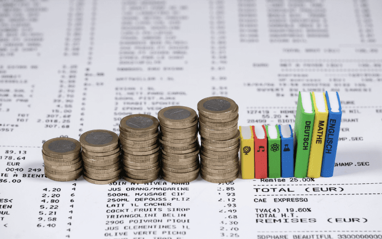 a pile of coins and textboook figurines illustrating the high costs of learning materials